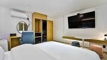 Una habitación de hotel moderna con una cama, un escritorio, un televisor, un armario y un equipo de aire acondicionado.