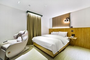 A modern hotel room with a bed, a massage chair, a bedside table with a phone, and a wall-mounted light fixture. - Gumi Wonpyeong-dong Number 25 (Gumi)