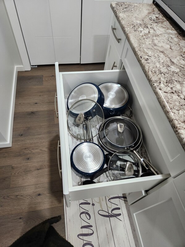 A kitchen drawer with various pots and pans.