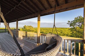 A wooden deck with a hanging hammock and a view of a green landscape. - Starlight Serenity - Hideaway with Stunning Views (Summerland Key)