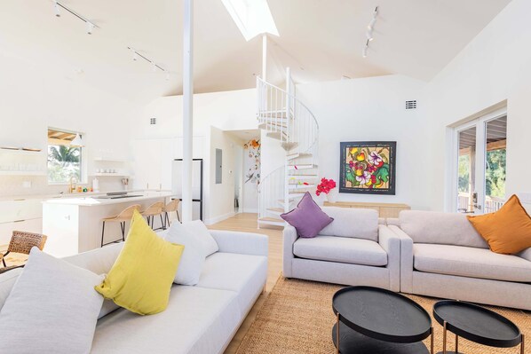 A spacious living area with a white sofa, a purple cushion, and a black coffee table. - Starlight Serenity - Hideaway with Stunning Views (Summerland Key)