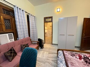 A living room with a sofa, a chair, a table, a wardrobe, and a radiator. - Mishra's Bungalow (Prayagraj)