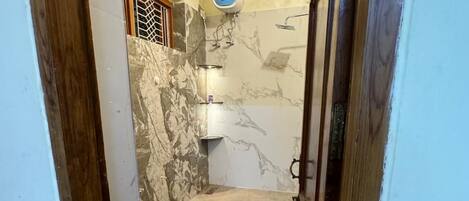 Un baño estrecho con inodoro, ducha y pared de mármol.