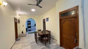 A hallway with a dining table and chairs, a ceiling fan, and a wooden door.