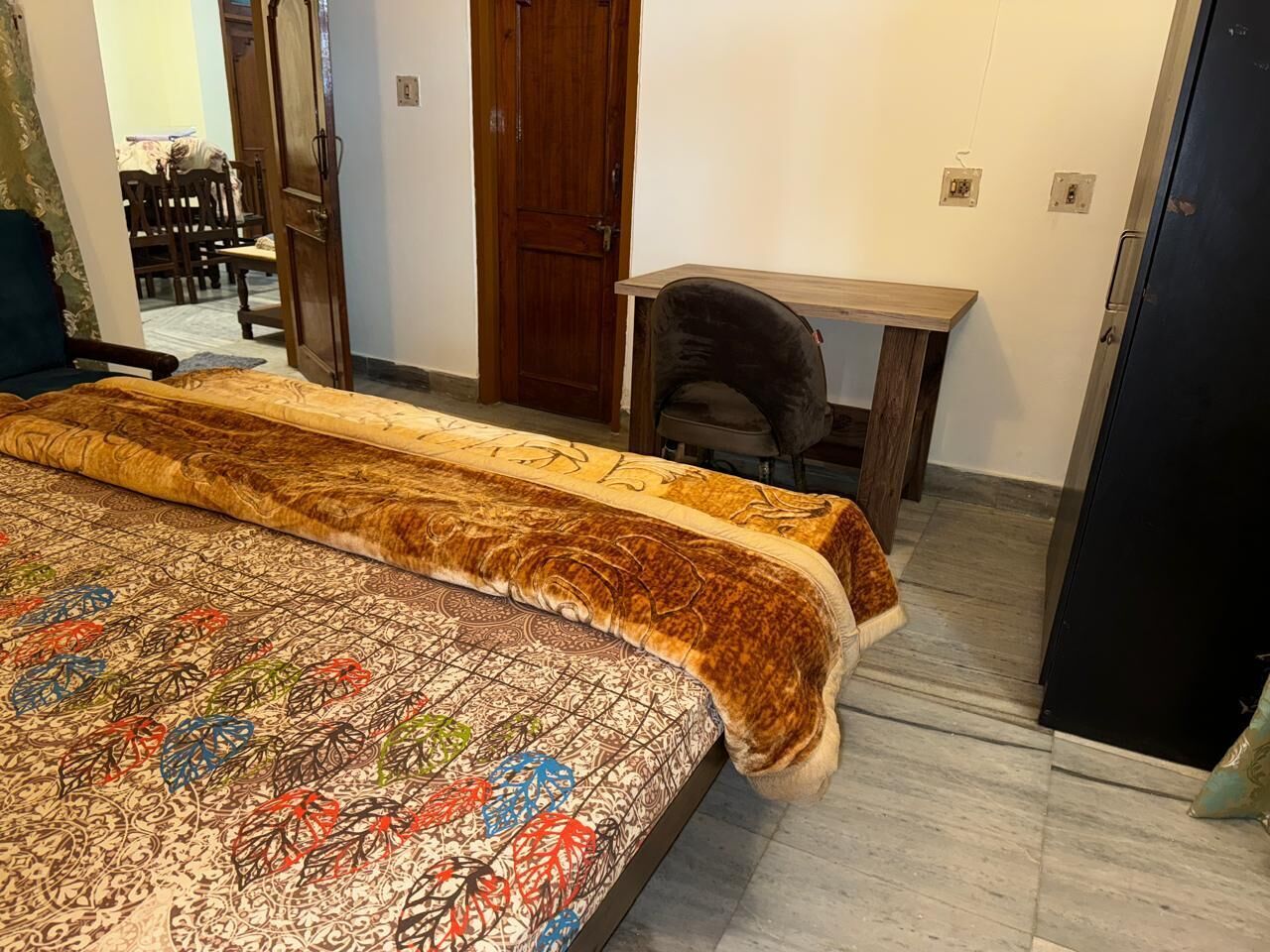 A bedroom with a large bed, a wooden desk, and a wardrobe.