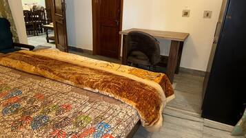 A bedroom with a large bed, a wooden desk, and a wardrobe.