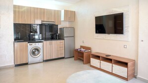 Une cuisine moderne avec des meubles en bois, un lave-linge, un four à micro-ondes, un réfrigérateur et un téléviseur encastré.