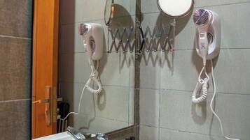 A bathroom with a sink, mirror, and two hair dryers mounted on the wall.