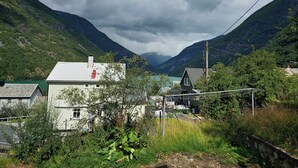 Une maison de campagne dotée d’un toit végétalisé, entourée d’une végétation luxuriante et avec des montagnes en toile de fond.