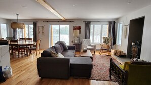 Un salón espacioso con sofá, reposapiés y un comedor con sillas y una mesa.