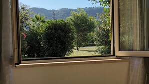 A room with a window overlooking a garden and hills. - Large 2 bedroom apartment close to swimming pool and beaches (Contrada Difesa II)
