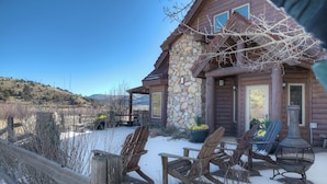 Un chalet rustique aux murs de pierre, doté d’une terrasse en bois et d’un espace salon extérieur.