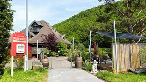 Un restaurant appelé « Eifeler Seehütte », doté d’un bâtiment rustique, de places assises en plein air et d’un chemin menant à l’entrée.