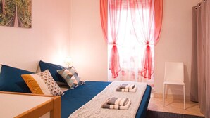 A bedroom with a bed, pillows, a bedside table, a lamp, a chair, and a window with sheer curtains. - Apartment for 2/3 people - Ney District, Angers (Angers)