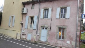 A pink building with multiple windows and doors, a visible street, and a signboard.