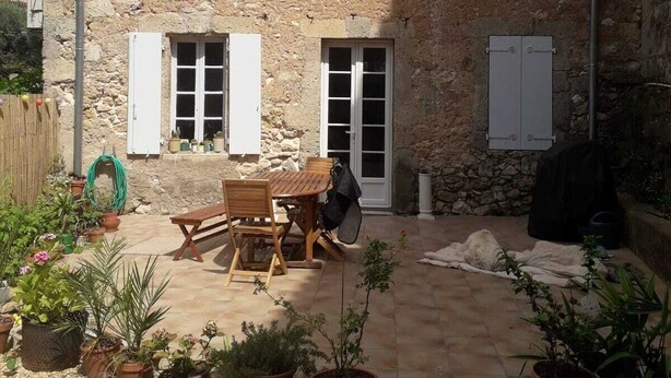 A stone building with a patio, outdoor seating, and potted plants.