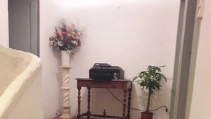 A staircase with a printer on a small table, a potted plant, and a floral arrangement.
