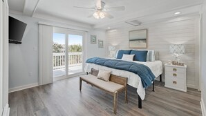 Ein Schlafzimmer mit Bett, Bank, Nachttisch und Deckenventilator.
