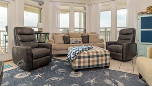 A living room with a beige sofa, two leather chairs, a plaid throw blanket, and a starfish-patterned rug. - Simple Pleasures, Gulf Beachfront, 3 Bedroom, 2 Bath (Dauphin Island)