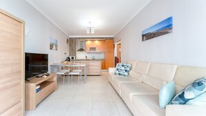 A compact living space with a kitchenette, a dining area, a sofa, and a TV. - Bright 1 BDR Flat W/ Pool & Balcony by LovelyStay (Portimão)