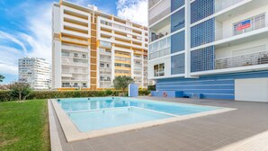 A modern apartment building with a swimming pool, balconies, and a blue and white color scheme. - Bright 1 BDR Flat W/ Pool & Balcony by LovelyStay (Portimão)