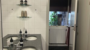 A bathroom with two sinks, a mirror, and a shower area.