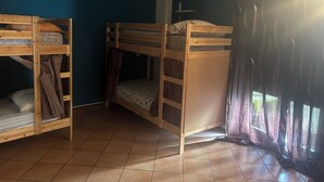 A room with two bunk beds, a small shelf, and a window with curtains.