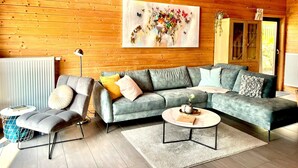 A modern living room with a grey sectional sofa, a grey armchair, a round coffee table, and a large abstract painting on the wall.