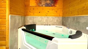 A wooden cabin with a sauna, a glass-enclosed tub, and a colorful abstract painting on the wall.