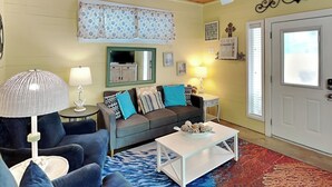 Un salon avec un canapé bleu, une table basse blanche et un tapis à motifs.