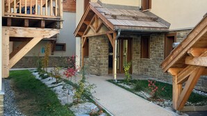 Ein traditionelles Chalet mit Holzbalkon, Steinwänden und einem Kiesweg.