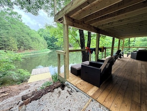 A wooden deck with wicker furniture overlooking a river, surrounded by trees.