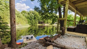 Un pontile in legno con sedie e tavolo che si affaccia su un lago, circondato da alberi.