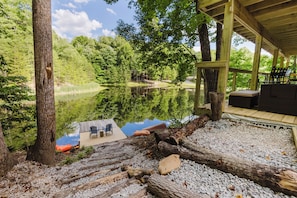 Un pontile in legno con sedie e tavolo che si affaccia su un lago, circondato da alberi.