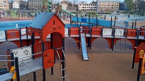 A playground with various play structures, including slides and climbing areas, surrounded by a fenced area. - 3-room 2 level family-/pet-friendly apartment in Riga with WiFi and parking (Riga)