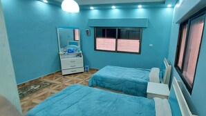 A room with two beds, a dresser, a window, and a mirror. - Modern Duplex In the center of Irbid (Irbid)