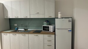 A modern kitchen with light wood cabinets, a stainless steel sink, a microwave, and a white refrigerator. - Le Suite di Giordy e Peppe 
4-bedroom apartment in charming Napoli with WiFi, AC (Napoli)