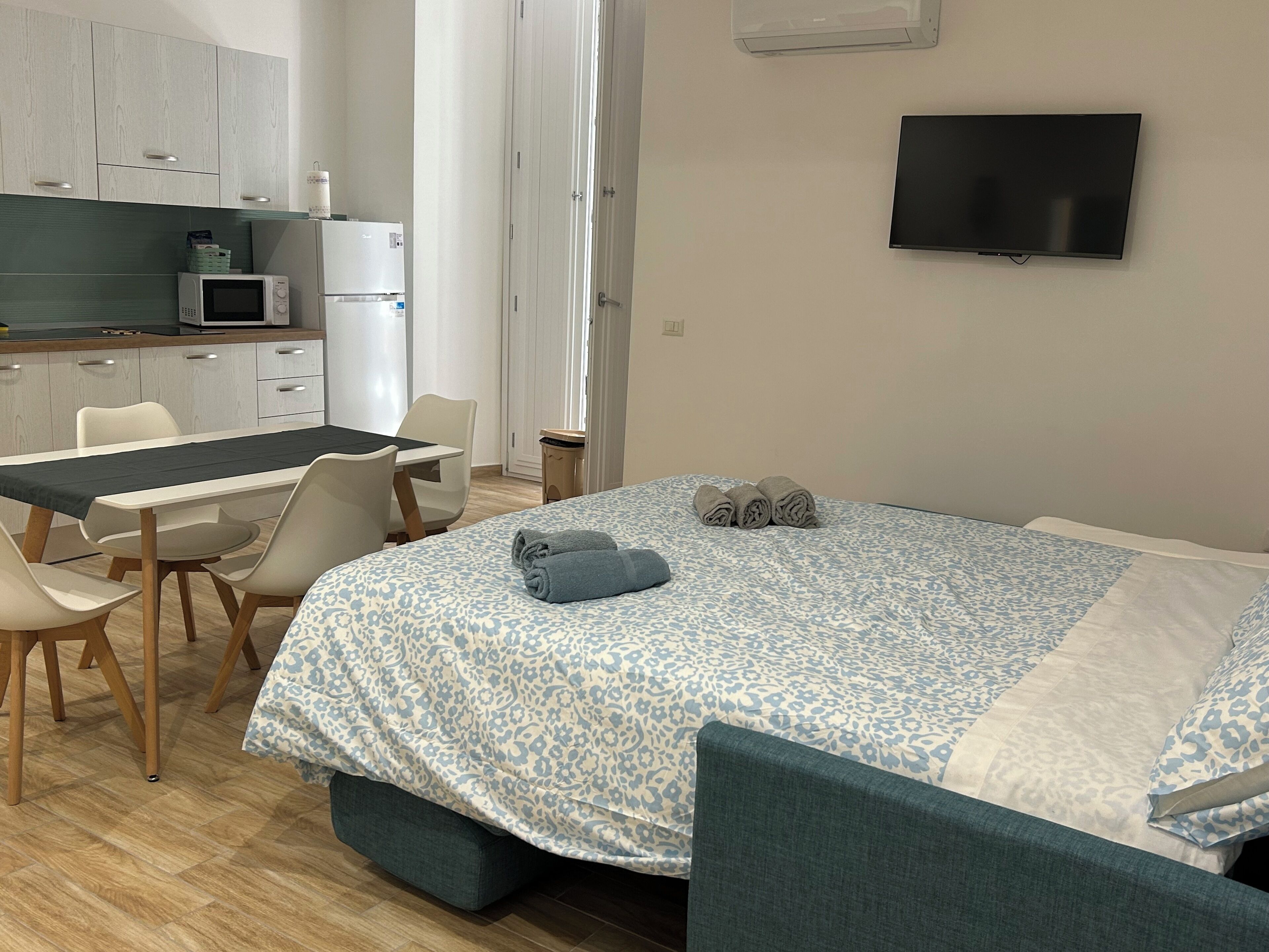 Une chambre avec un lit, une télévision, un bureau et un coin cuisine.