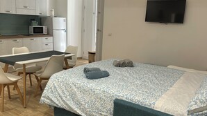 A bedroom with a bed, a TV, a desk, and a kitchenette. - Le Suite di Giordy e Peppe 
4-bedroom apartment in charming Napoli with WiFi, AC (Napoli)