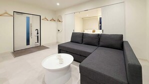 A modern living room with a grey sectional sofa, a white coffee table, and a door with a blue accent.