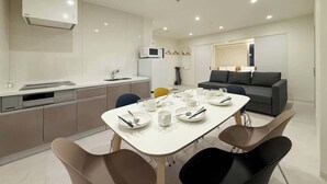 A modern kitchen with a dining area, a grey sofa, and a microwave.
