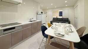 A modern kitchen with a dining area, white cabinets, and a grey sofa.