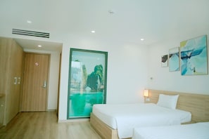 A hotel room with a bed, a bedside table, a window with a view of a body of water, and a door. - Kim Sentral Hotel (Bai Chay)