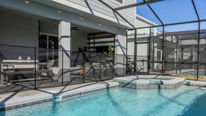 Una piscina amb una zona d'estar integrada, un porxo cobert i vista a un edifici modern.