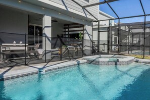 Una piscina con una zona de estar hundida, un porche cubierto y vistas de un edificio moderno.