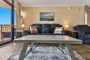 A living room with a sofa set, a coffee table, and a painting on the wall. - Ocean Reef Resort Unit 919 (Myrtle Beach)