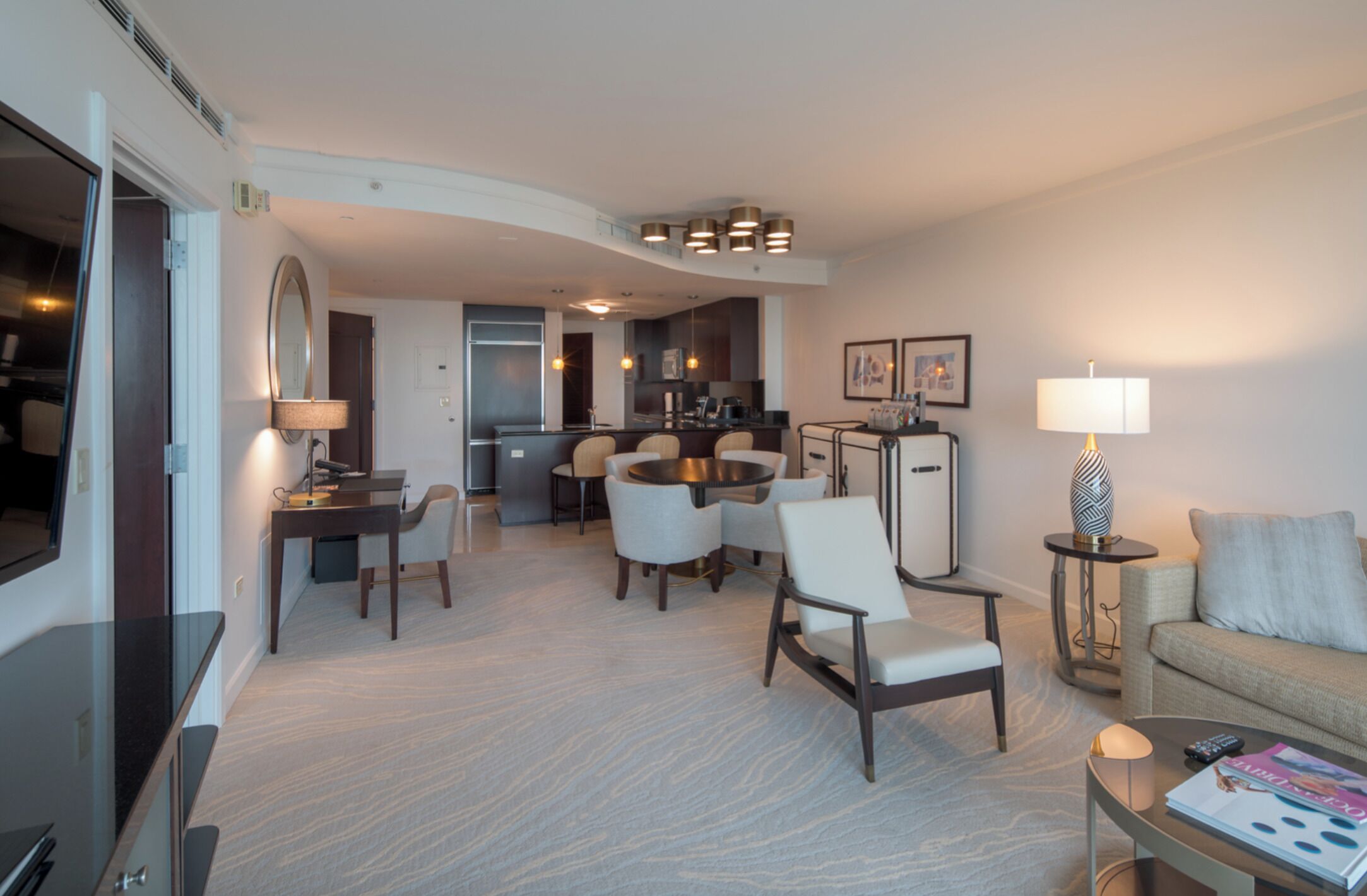 Et moderne hotelværelse med spiseplads, en sofa, et sofabord og et fjernsyn.