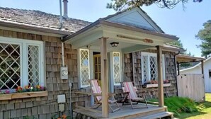 Une maison dotée d’un porche abrité, de deux fenêtres ornées de motifs en treillis et d’une cheminée.