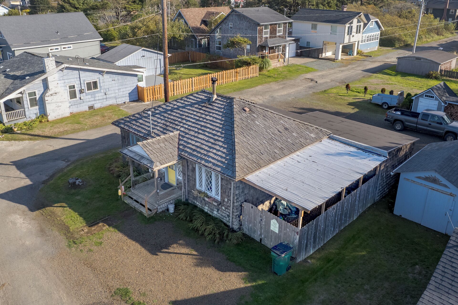 A residential property with a large detached house, a fenced backyard, and a gravel driveway.