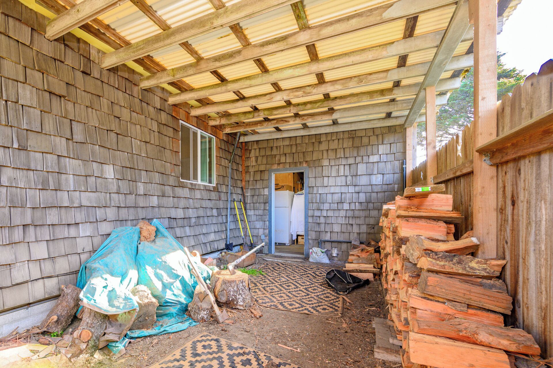 A room with a wooden shingled exterior, a metal roof, and a door leading to another room.